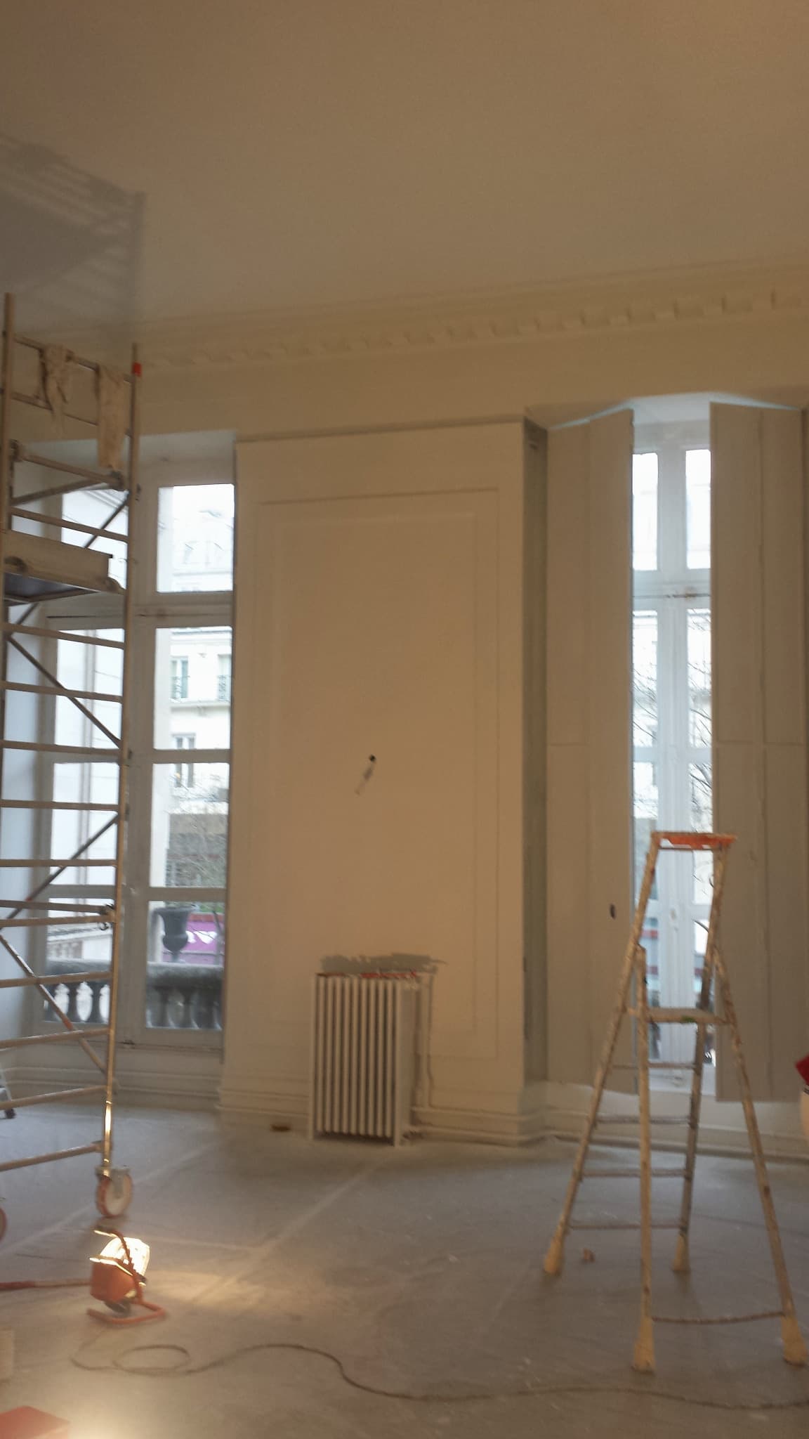 Pièce en chantier, moulures conservées, échafaudage et protection des sols.
